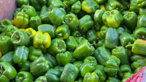 una vibrante pila de pimientos verdes frescos listos para la venta en el mercado.