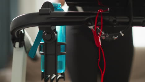 mujer corre en una cinta de correr con una botella de agua en el gimnasio de primer plano. mujer deportiva utiliza equipos de entrenamiento modernos para cuidar el cuerpo en casa en cámara lenta
