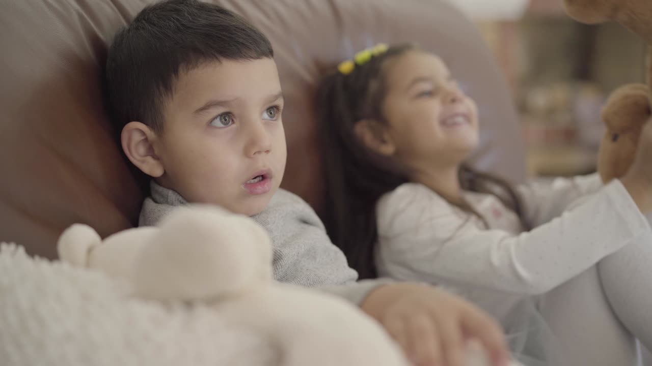 rostro en primer plano de un lindo niño de oriente medio sentado con su hermana en el entrenador y jugando a los juguetes