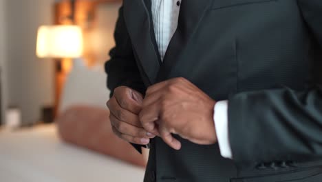 Groom-buttoning-his-suit,-getting-dressed-in-the-room