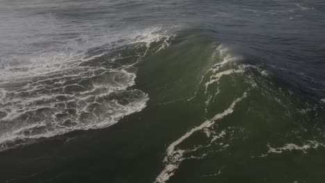 Vista-Aérea-Del-Despegue-De-Surfistas-Y-Montando-Una-Gran-Ola-En-Nazaré,-Tiro-A-Cámara-Lenta