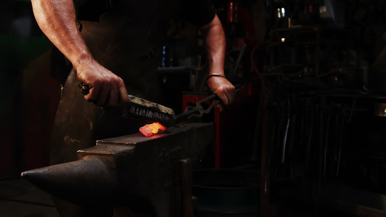 sección media del herrero usando pincel de alambre en hierro caliente