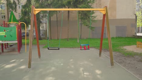 Dangling-swing-on-playground-during-summer-in-handheld-slowmotion-childhood-memory