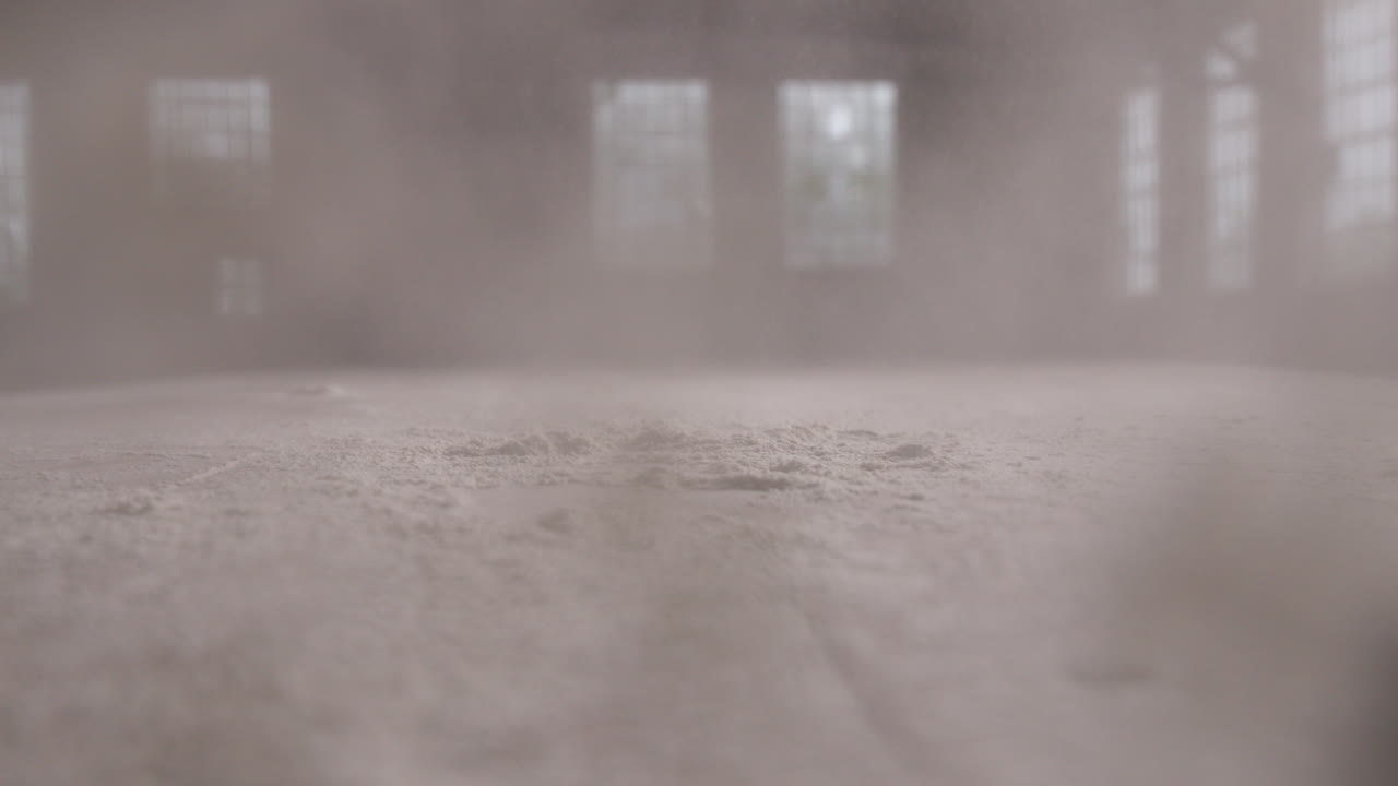 Slow motion footage of a pile of flour being smashed with a hand and the flour covers the camera lens.