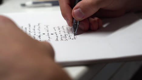 mano y pluma escribiendo poema en papel
