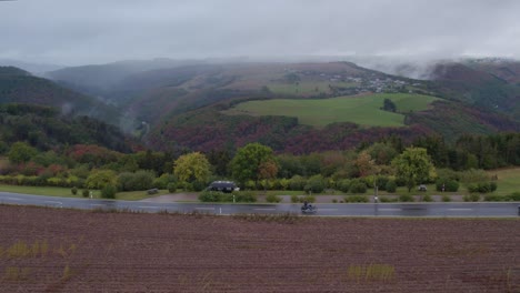 motorbikes cruising at small road at bourscheid luxembourg on cloudy day, aerial