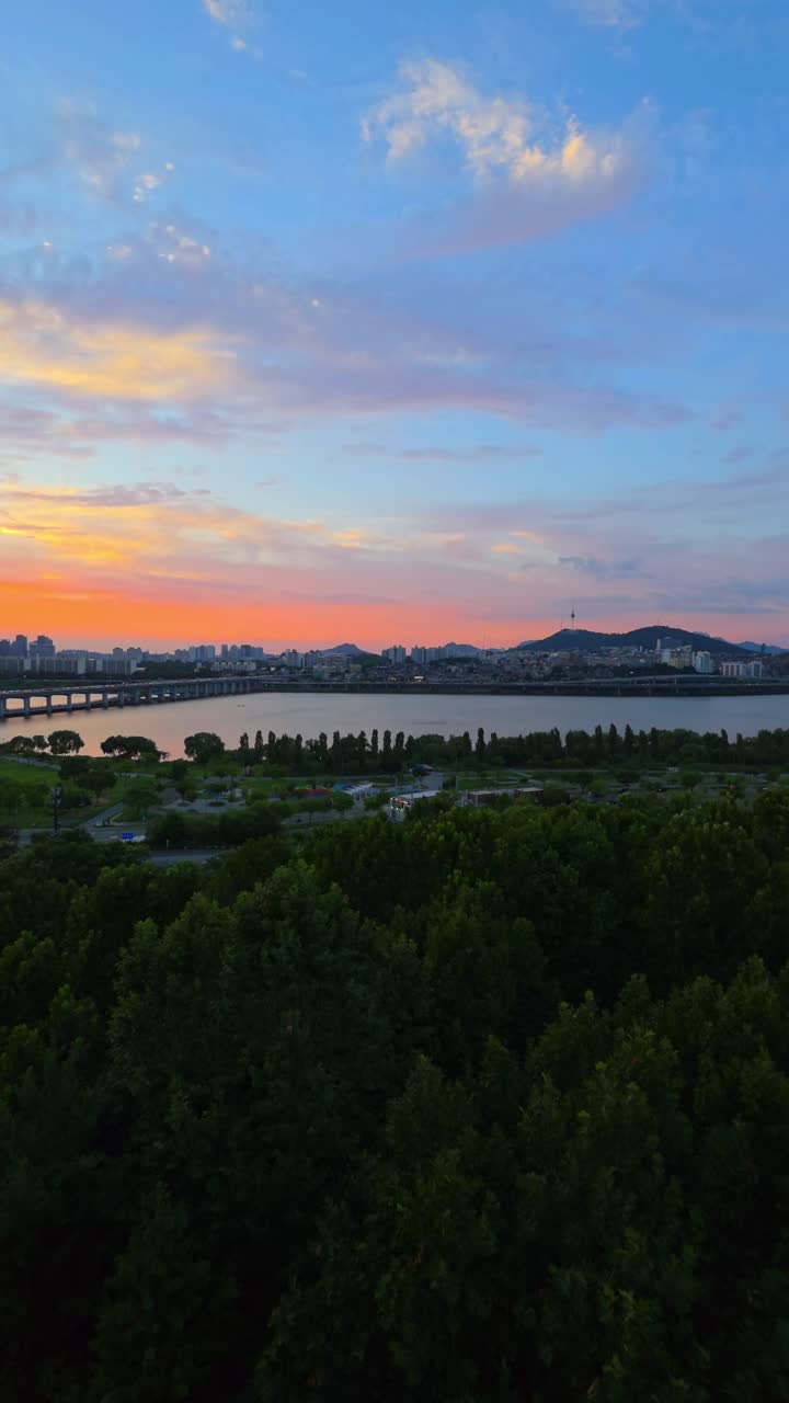 Colorful clouds above Seoul skyline during sunset, panning from Banpo Bridge to Namsan Tower with lush Hangang Park