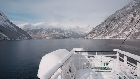 Slow-motion-POV-of-a-winter-ferry-boat-ride-in-Geirangerfjord-to-Geiranger,-Norway,-with-snowy-mountains-and-captivating-fjord-views