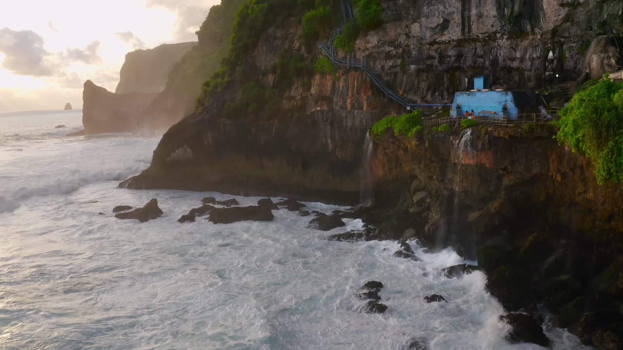 impresionante toma aérea de las cataratas nusa penida guyangan durante la puesta de sol y la hora dorada, mientras las olas rompen en los acantilados