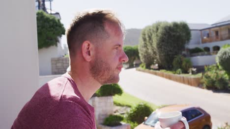 caucasian man drinking coffee on balcony in the sun