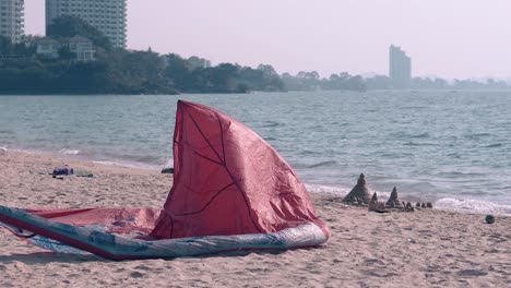 ala roja de kitesurf ondeada por el viento en la playa de arena del océano