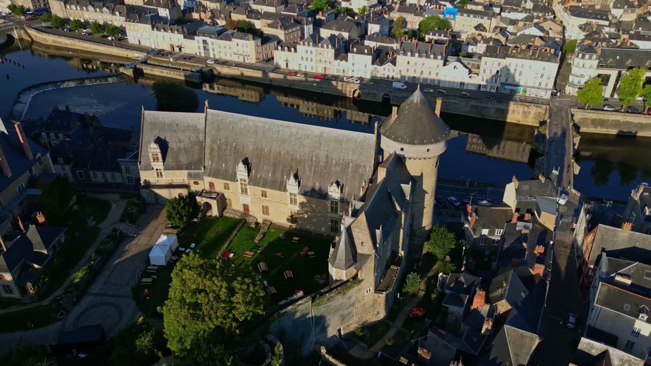 Aerial drone of historic Château de Laval, medieval castle, keep, and Mayenne river at golden hour, Laval, France