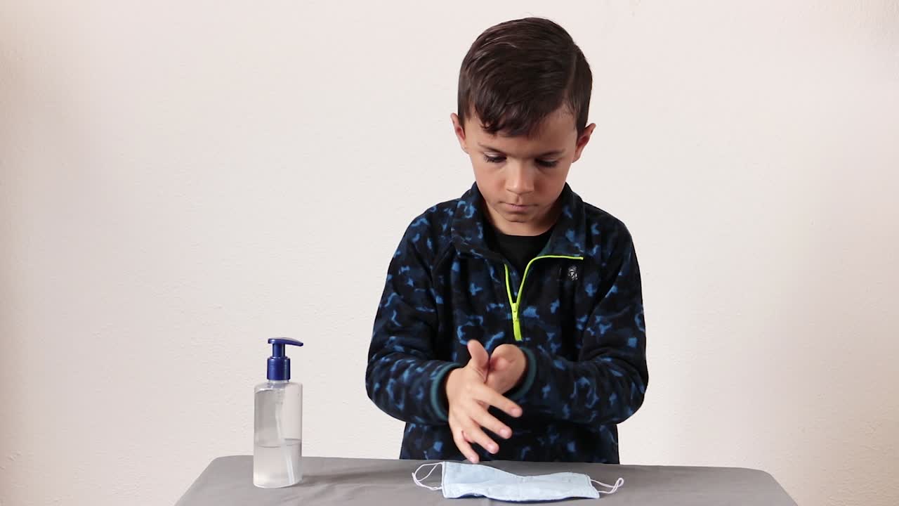 아름다운 어린 소년은 covid-19 바이러스에 대해 부지런히 손을 소독합니다