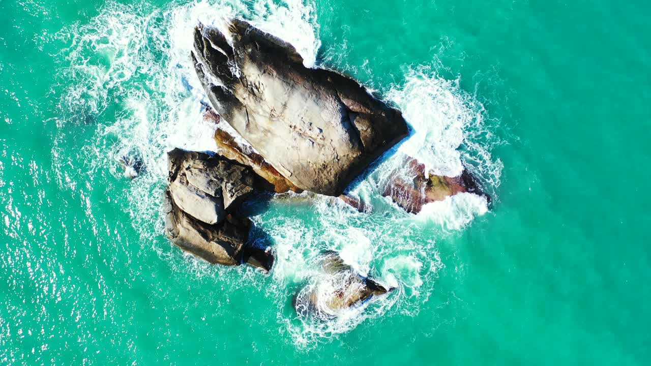 Beautiful limestone cliffs splashed by turquoise ocean foaming water on shore of tropical island in Thailand