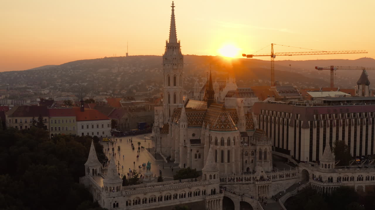 Il sole scompare dietro la silhouette della Chiesa di Mattia, proiettando un tranquillo bagliore arancione sul paesaggio