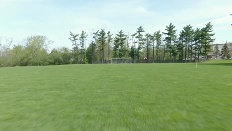 reverse moving shot across a soccer field through a ripped part of the opposing net in the goal