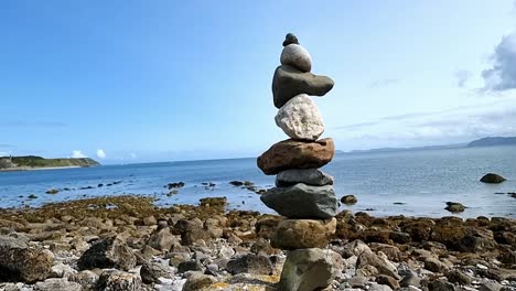 Zen-ausgeglichene-Steine,-Die-über-Den-Sonnigen,-Friedlichen,-Blauen-Himmel-Und-Den-Sommerstrandhorizont-Ragen
