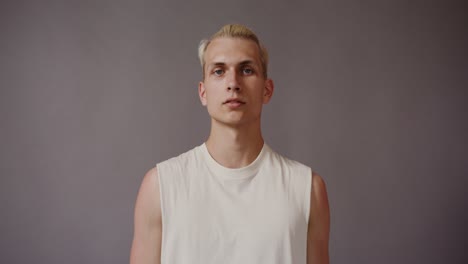 portrait of a young man with blonde hair wearing a white sleeveless shirt