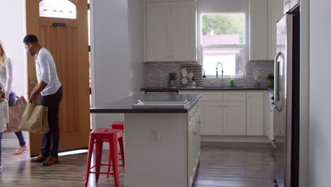 Girl-and-mixed-race-parents-unpack-shopping-bags-in-kitchen,-shot-on-R3D