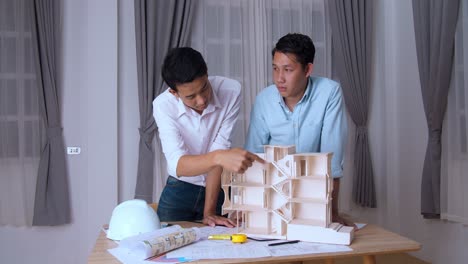 two architects standing at a desk and discussing a project