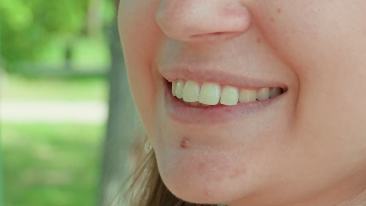 Feliz mujer caucásica disfrutando de la luz natural en exteriores; primer plano de una alegre señora caucásica con los dientes visibles, disfrutando de la luz natural en un parque.
