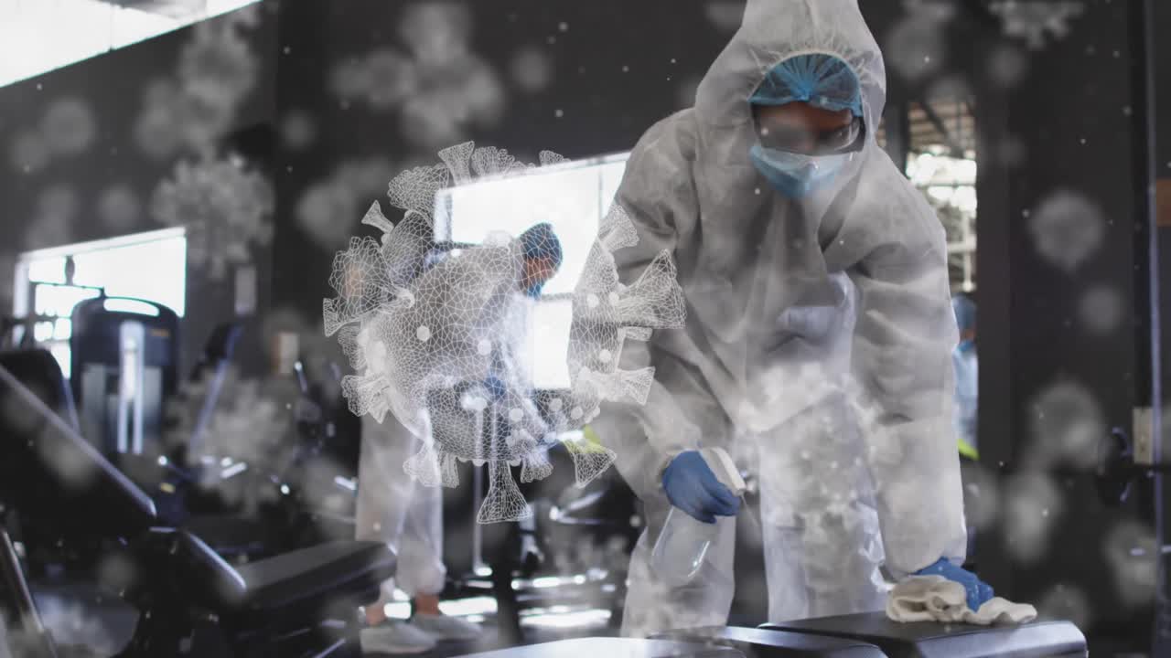 여러 개의 코로나19 세포가 소독제를 사용하여 체육관을 청소하는 보건 노동자 그룹 위에 떠다니고 있습니다.