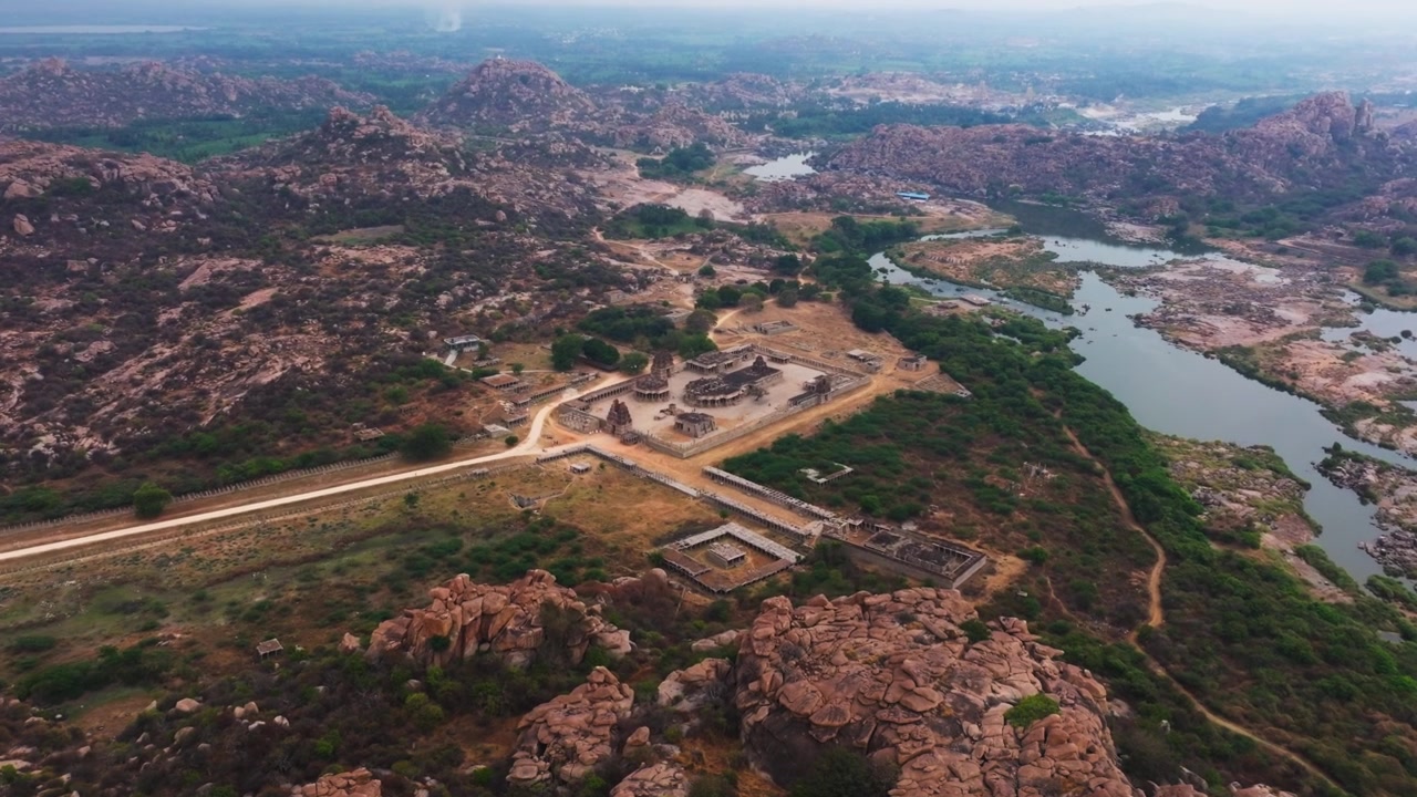 Sri Bhashyakara (Ramanuja) Gudi med Haleya Mantapa, Steinvognen, Maha Mantapa musikkpilarer og elven ved Hampi, Karnataka, India. Dagtid, innzooming, droneopptak, 4K.