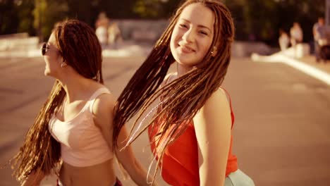 dos mujeres felices con miedos caminando por la carretera vacía y hablando en verano. dos chicas hipster riendo y bailando durante un