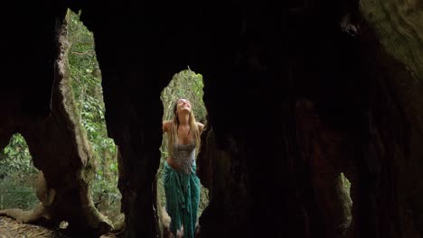 gorgeous woman in between holes of bulky roots - wishing tree of lamington national park in gold coast, qld, australia