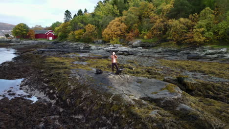 aerial footage closing in on a man standing at the shore and taking pictures with a camera