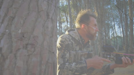 man in camouflage holding crossbow in forest with data overlay animation