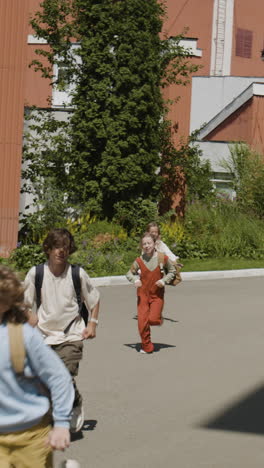 children running with backpacks outside school