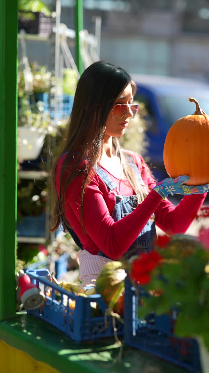 mujer sosteniendo una calabaza en un mercado de agricultores