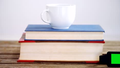 libros, taza de café, y reloj inteligente en una mesa de madera 4k