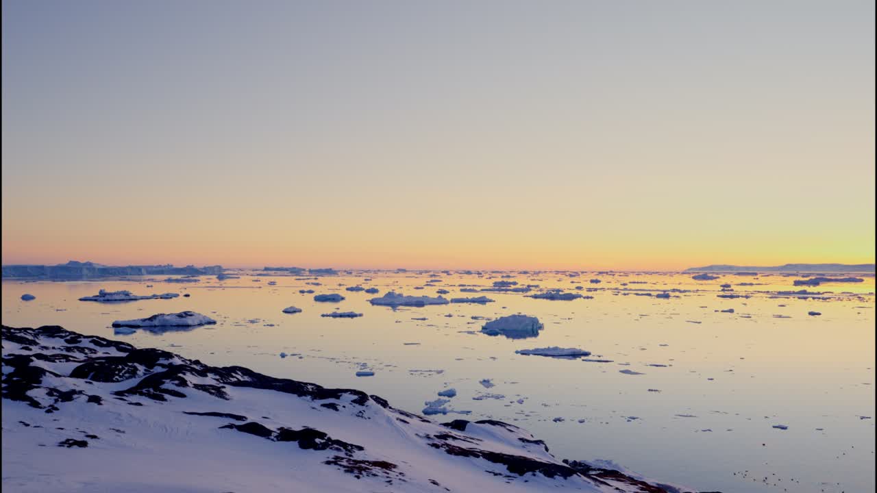イルリサット・アイスフィヨルドの夕暮れ時の雪に覆われた海岸線。