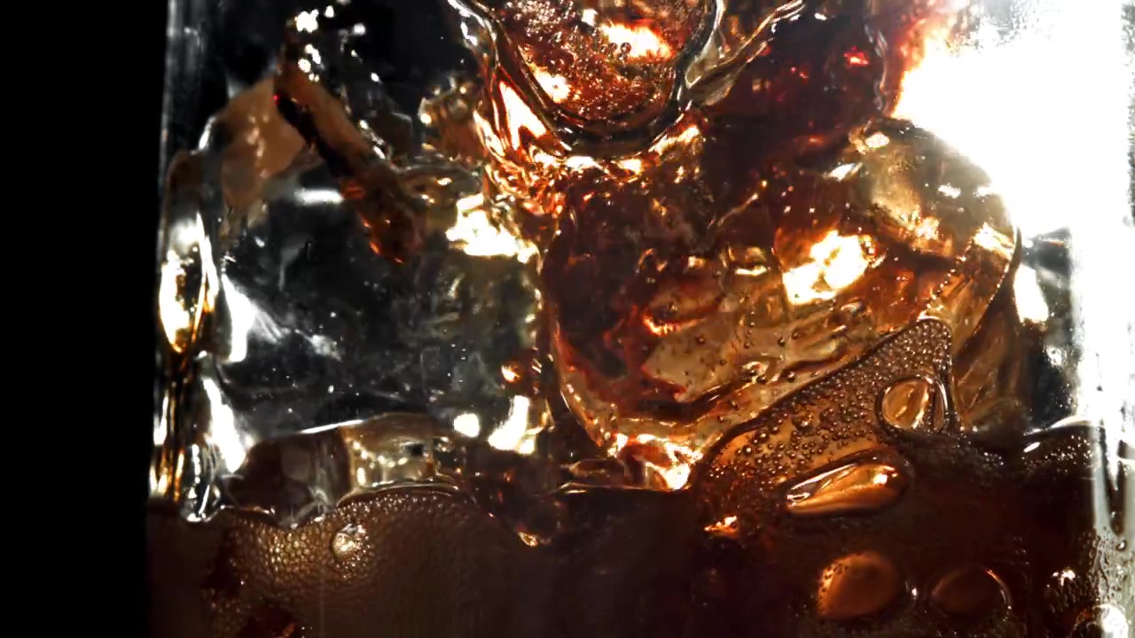 Cola foncé rafraîchissant avec des glaçons et des bulles dans un verre