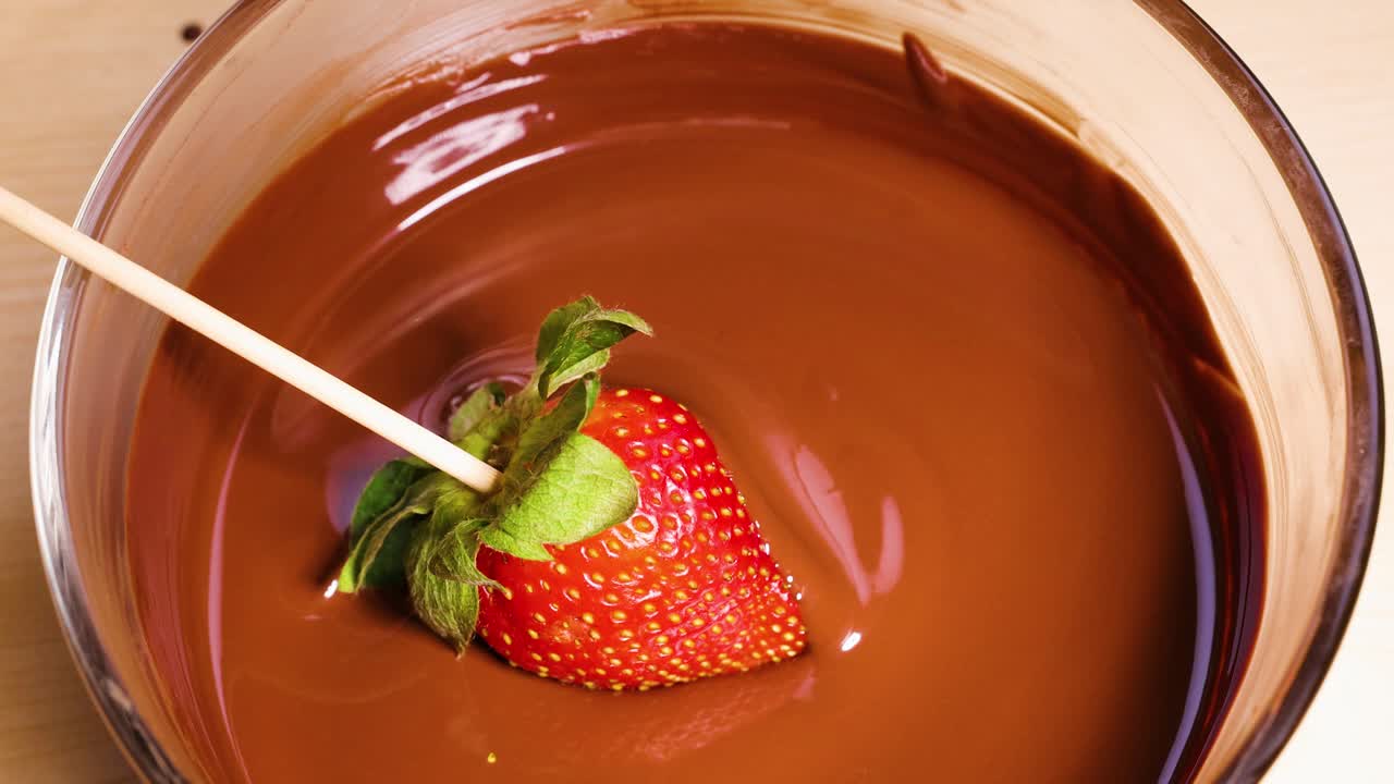 녹은 초콜릿 에 딸기 를 담그고 있는 것