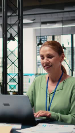 vertical video modern entrepreneur reviewing project analytics and progress on her laptop