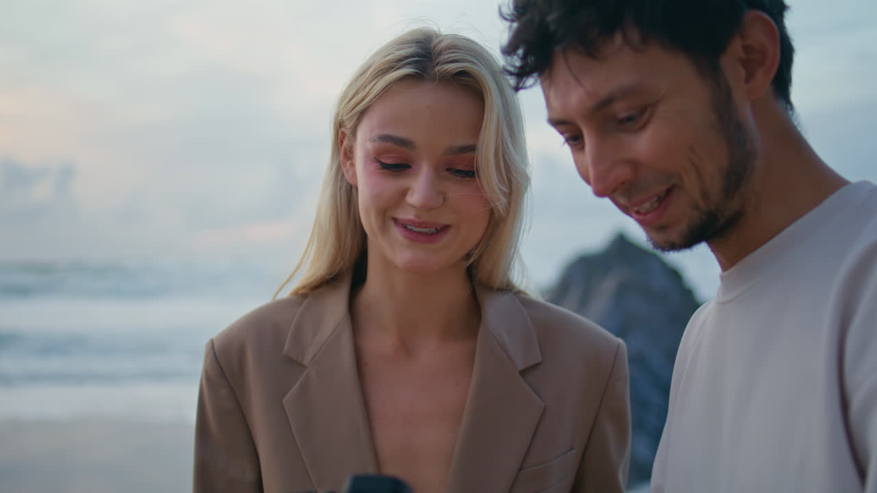 사진작가는 해가 지는 동안 아름다운 모델에게 카메라 사진을 보여줍니다.