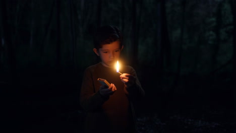 a young boy illuminates the dark forest with a lit match