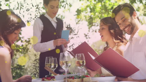 animación de puntos amarillos sobre felices amigas y amigos caucásicos ordenando en un restaurante