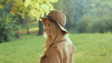 Kaukasische-Junge-Blonde-Frau,-Die-Im-Herbst-Im-Park-Spaziert-Und-Sich-Mit-Einem-Netten-Kleinen-An-Die-Kamera-Wendet