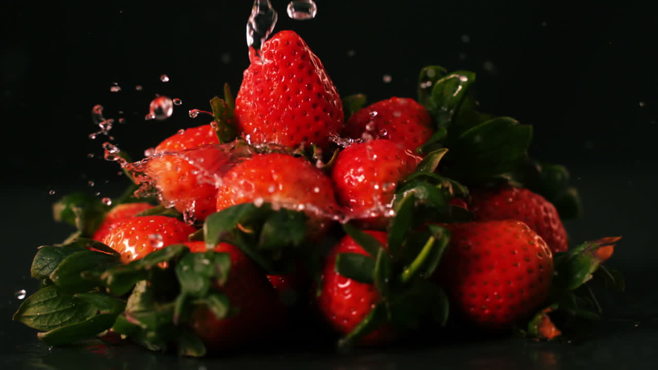 Gocce d'acqua su fragole su superficie nera