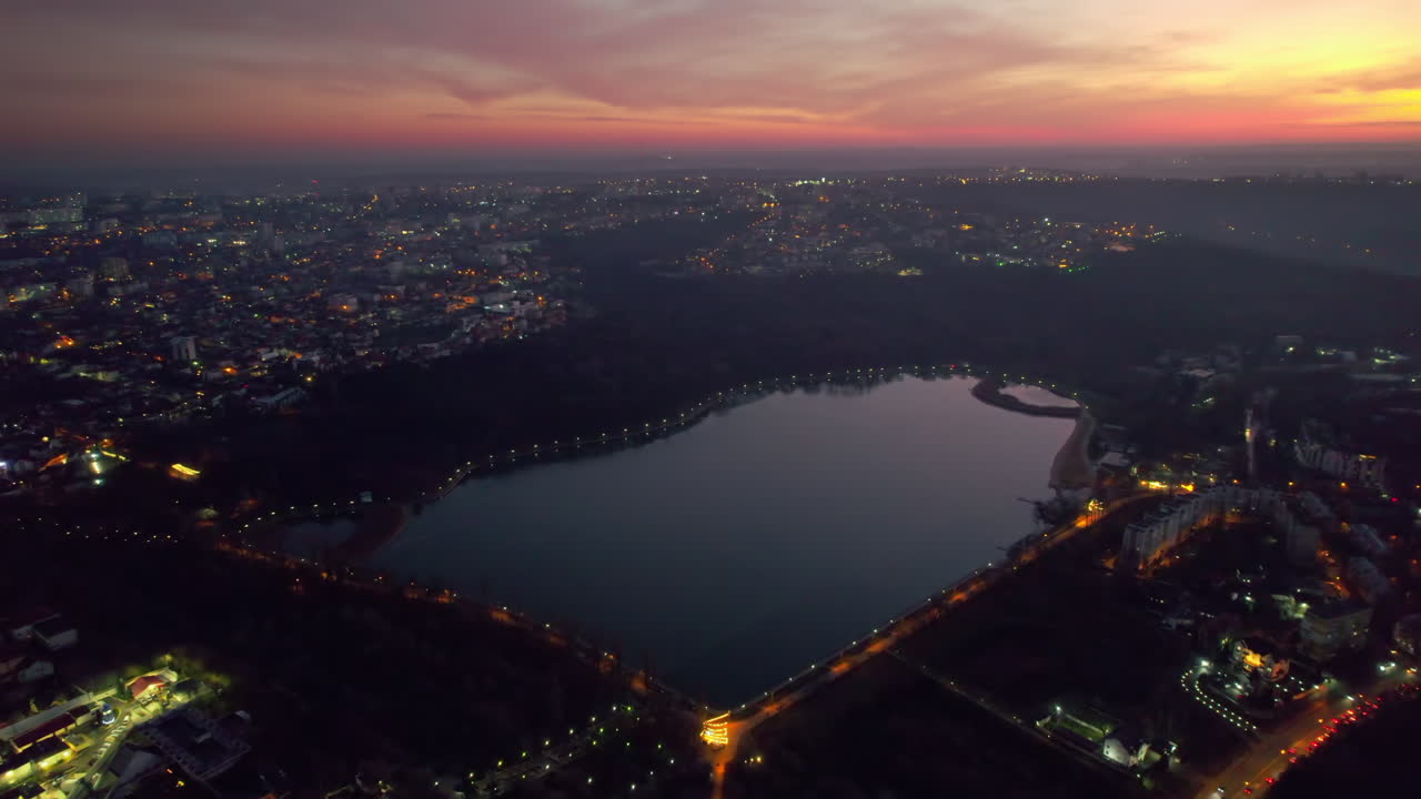 Aerial drone view of Chisinau at sunset, Moldova. View of city centre with lake, buildings, roads, illumination