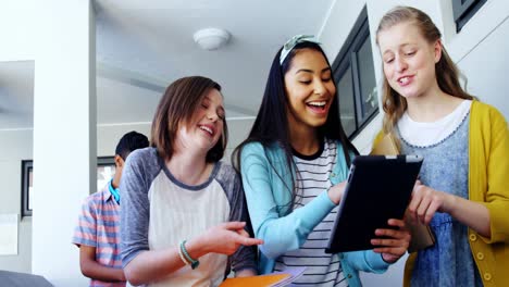 grupo de amigos de la escuela que usan una tableta digital en el pasillo