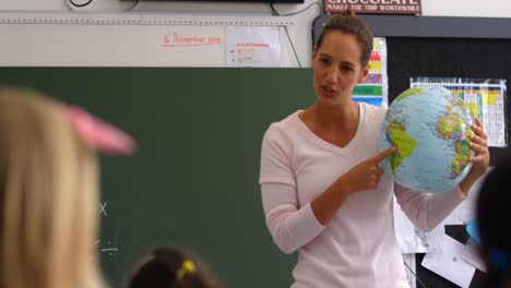 Vista-Frontal-De-Una-Profesora-Caucásica-Explicando-Sobre-El-Globo-Terráqueo-En-El-Aula-4k