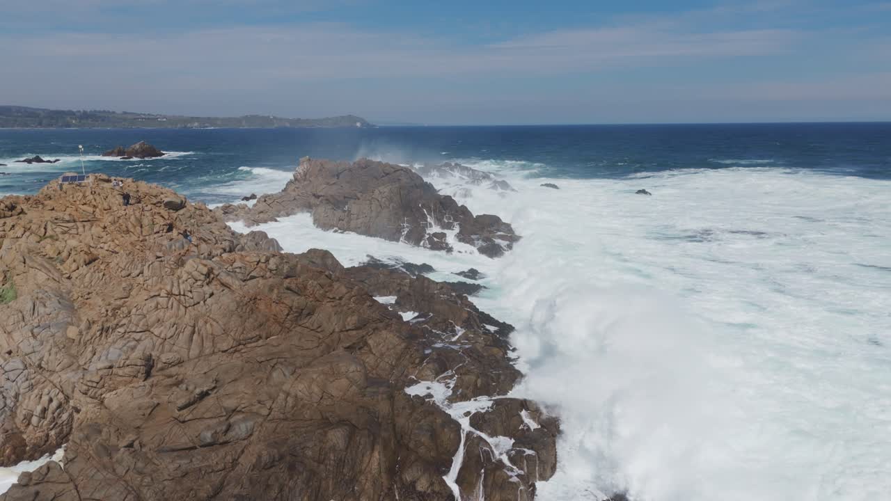 Dynamic aerial view capturing powerful waves crashing against rocks at Playa Chica in Quintay, showcasing the stunning coastline of Casablanca, Valparaíso, Chile.