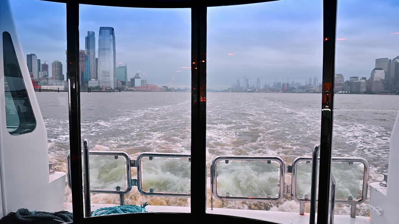 Travel by the river in New York on grey dull day. A view through the window at the back of the boat on the turbulent waterscape