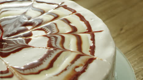 Closeup-tasty-round-dessert-covering-with-sugar-and-chocolate-syrup.