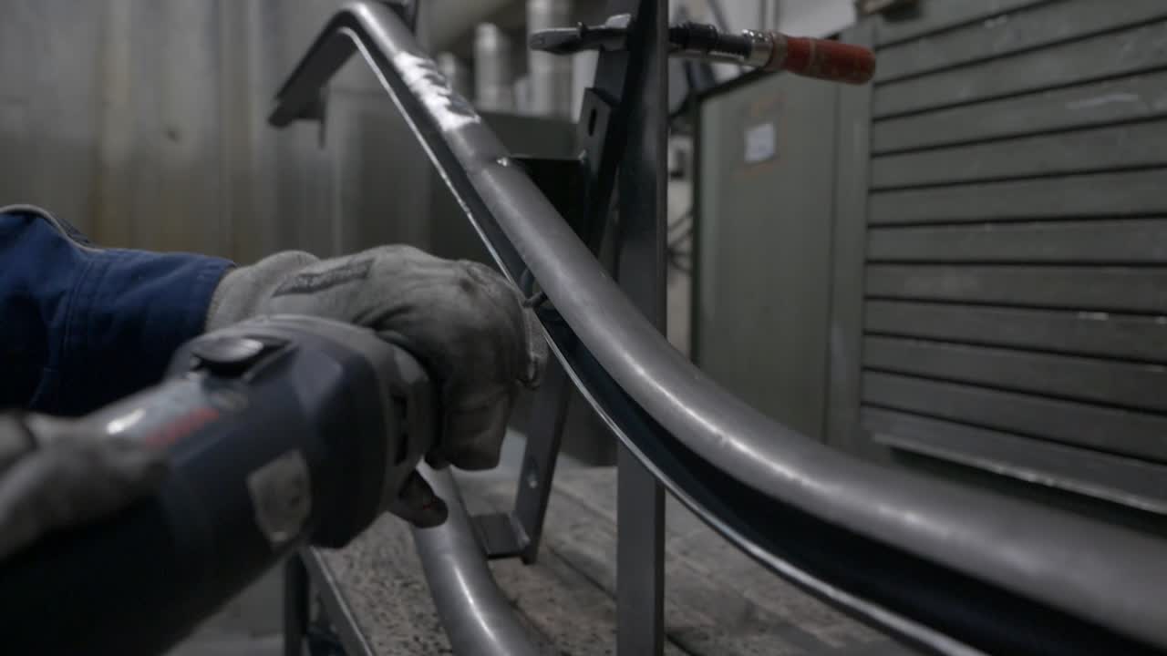 pulir la parte interior de un tubo de metal curvo con un pequeño molinillo eléctrico de mano - cerrar